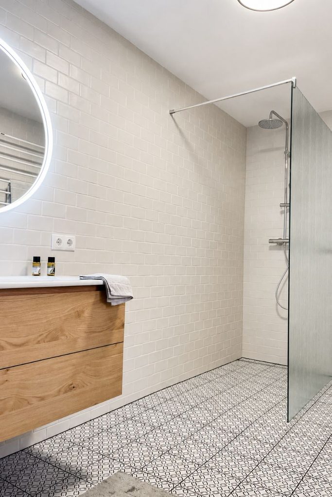 Gästebad im Altbau mit bodengleicher Dusche, weißen Metro-Fliesen und gemusterten Bodenfliesen