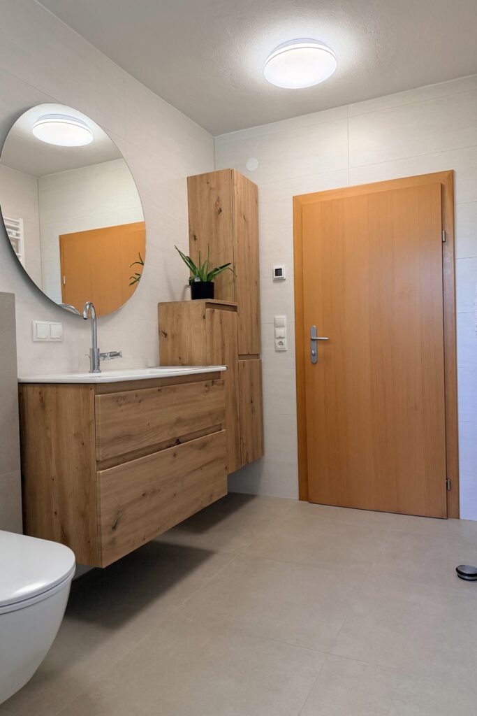 Modernes Badezimmer nach der Komplettsanierung mit Holz-Waschtisch und großformatigen Fliesen in Hartberg